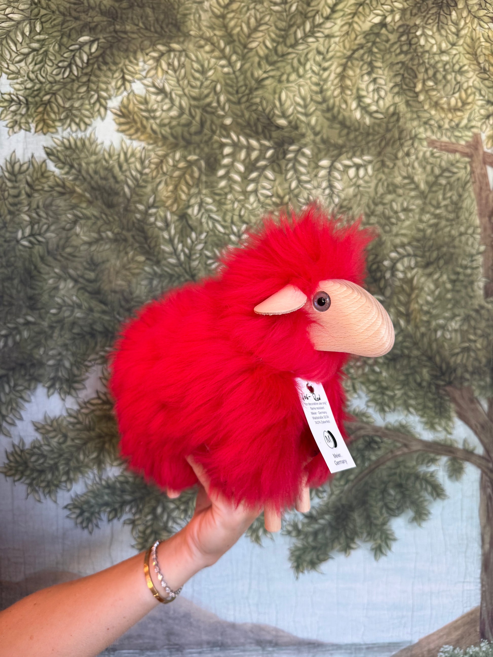 Red fur tiny lamb held in a hand with its swing tag showing