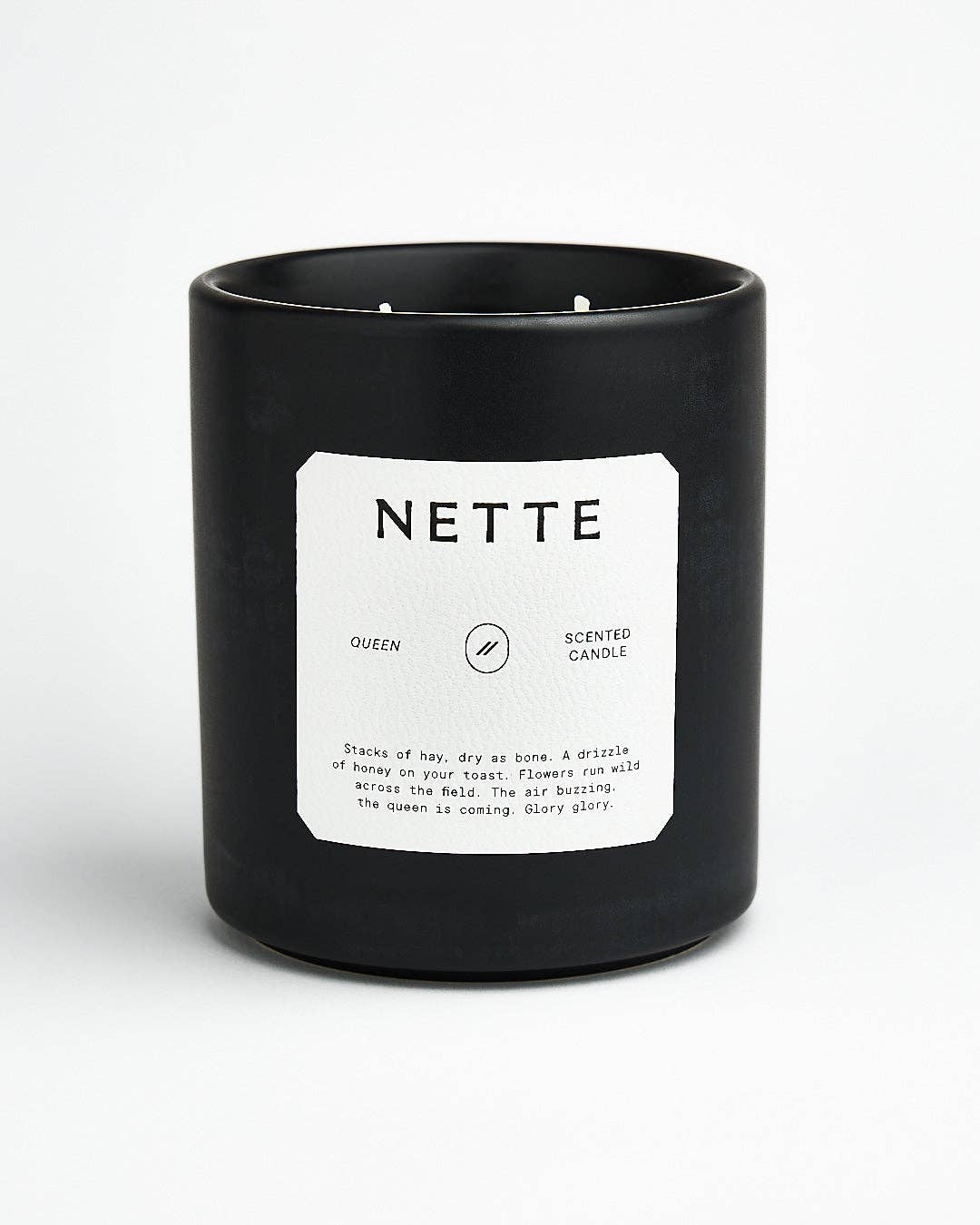 Queen candle in a black ceramic jar with a white Nette label
