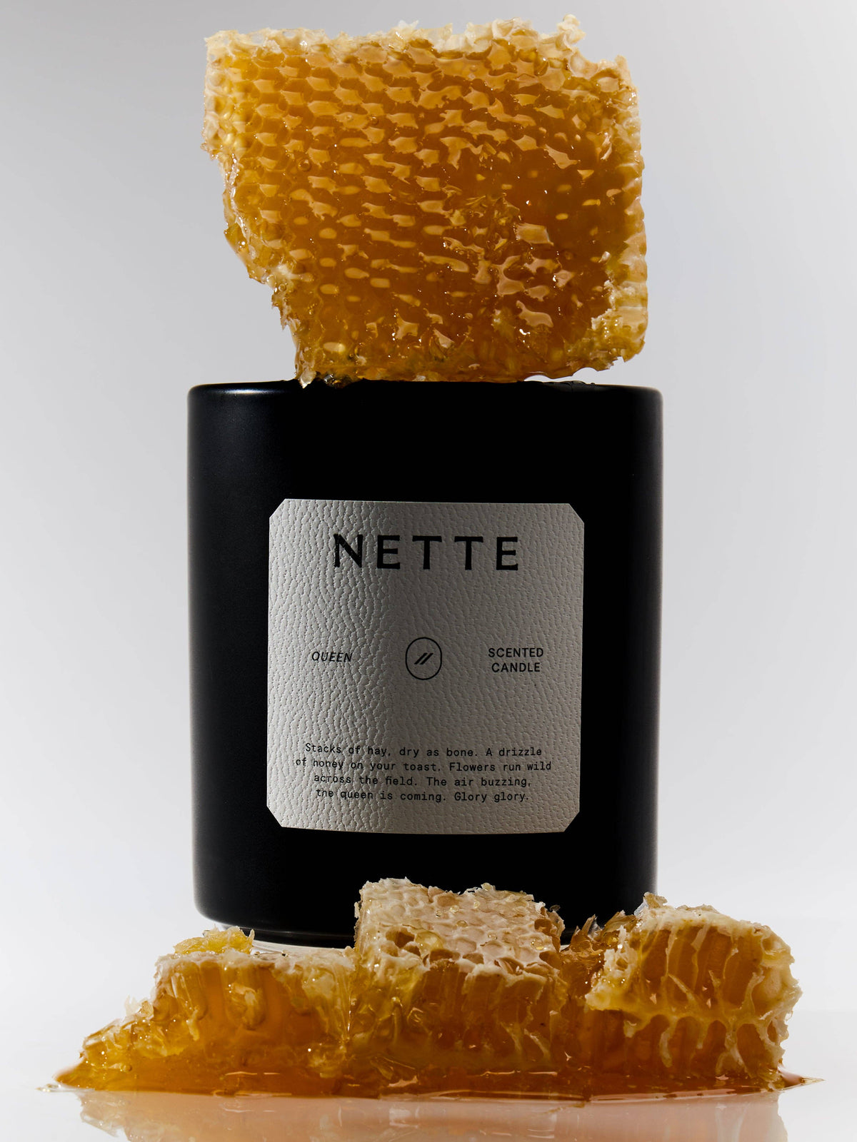 Queen candle with a piece of honeycomb balanced on top of the jar